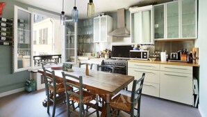 A modern kitchen with a dining area, featuring a large window, a stove, and a microwave.