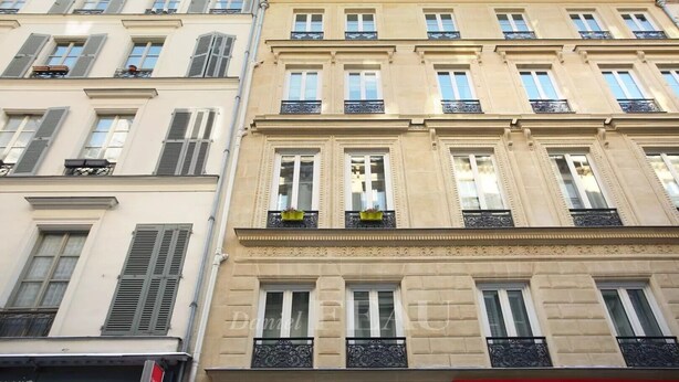A multi-story building with symmetrical window designs, balconies with wrought iron railings, and decorative moldings.