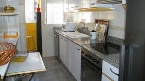 A compact kitchen with a sink, microwave, stove, and a small dining table.