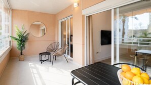 Ein Balkon mit Tisch, Stühlen, einer Topfpflanze und einem Korb voller Obst.
