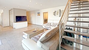 Un salon moderne avec un téléviseur à écran plat, un canapé et un escalier.