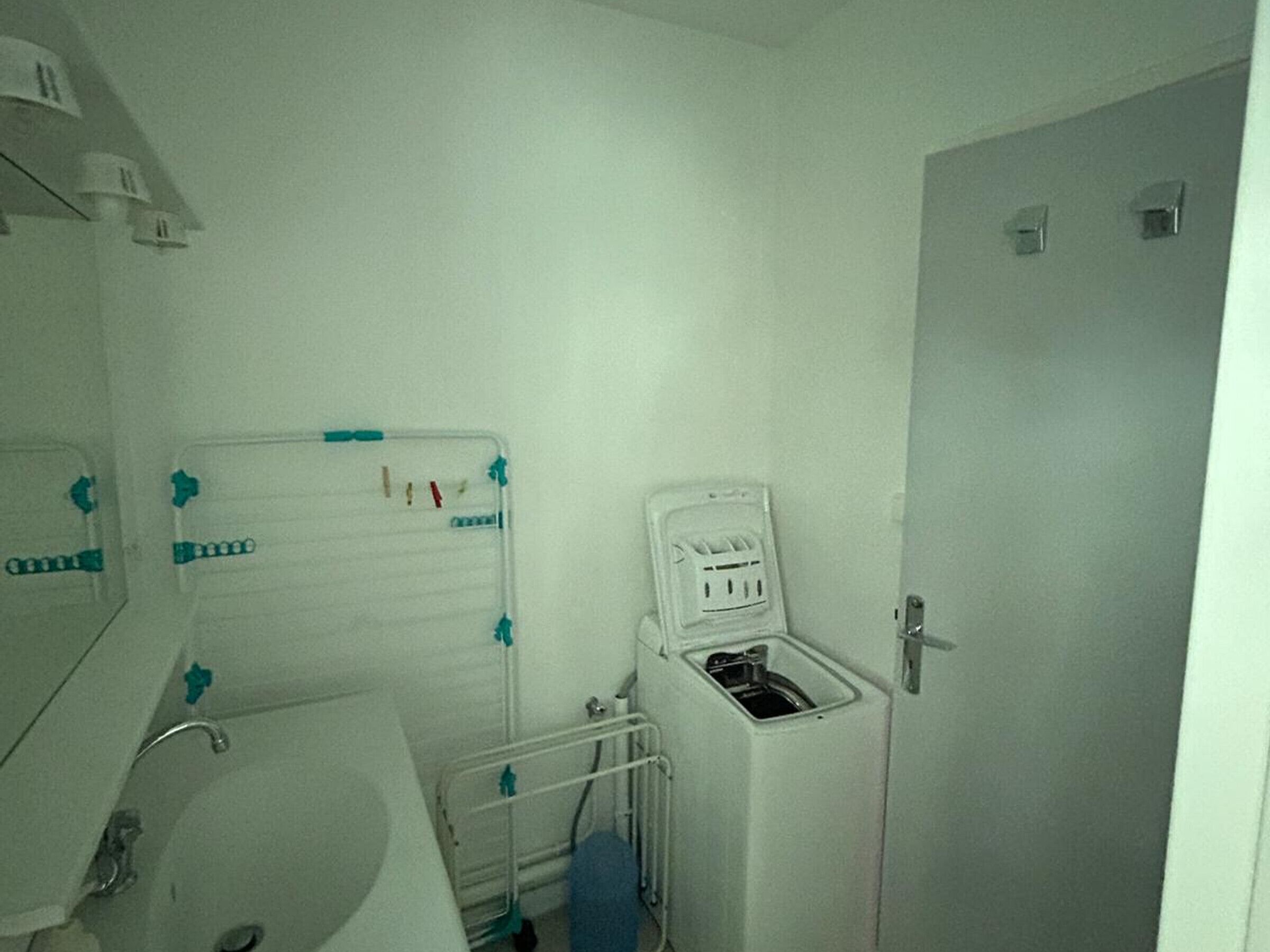 Ein kleines, sauberes Badezimmer mit Waschbecken, Spiegel und einer weißen Toilette mit Fußstütze.