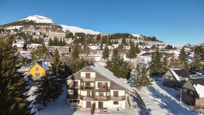 Een met sneeuw bedekte berg met een chalet en een gebouw met twee verdiepingen op de voorgrond.