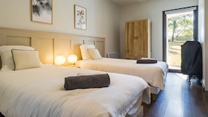 Habitación de hotel con dos camas, un armario de madera y vistas al exterior.