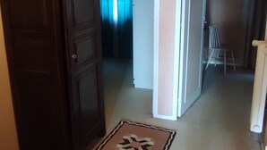 Un couloir avec une porte en bois, un tapis à motifs et un mur blanc.