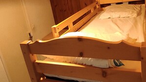 A wooden bunk bed with a headboard, a bedside table, and a wall-mounted lamp. - Ski-in/ski-out studio for 4 people (Besse-et-Saint-Anastaise)