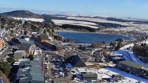 A town with a lake, buildings, and snow-covered hills. - Ski-in/ski-out studio for 4 people (Besse-et-Saint-Anastaise)