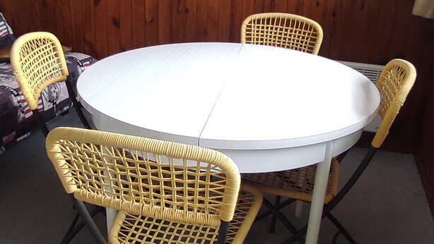 A round table with four wicker chairs, a white tablecloth, and a wooden wall in the background. - Ski-in/ski-out studio for 4 people (Besse-et-Saint-Anastaise)