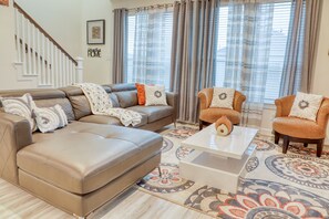 A living room with a brown leather sofa, two armchairs, a coffee table, and a patterned rug.