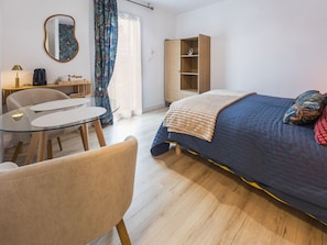 A bedroom with a bed, a bedside table, a chair, a small table, a mirror, a wardrobe, and a window with curtains. - Cozy room with private terrace and wifi in Missillac (Missillac)