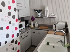Compact kitchen with a sink, microwave, coffee maker, toaster, and utensil storage.