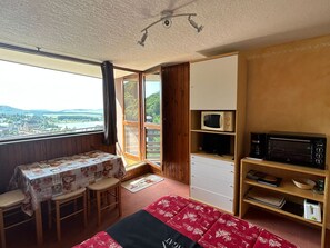 Una habitación con una cama, una mesa con sillas, un microondas, un tostador y vistas a un paisaje.