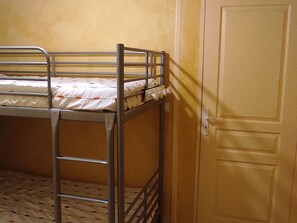 A bunk bed with a ladder, a door, and a wall with a textured finish.