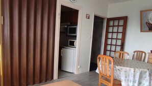 Ein Essbereich mit Tisch, Stühlen, einer Bank, einer Mikrowelle und einem Kühlschrank im Hintergrund.