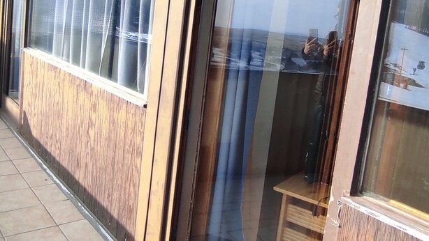 Eine Außenwand aus Holz mit Fenster, Glastür und einem kleinen Holztisch.