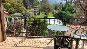 A patio with a table and chairs, a metal fence, and a view of a garden and distant buildings. - Air-conditioned villa with private pool and pets allowed (Saint-Génis-des-Fontaines)
