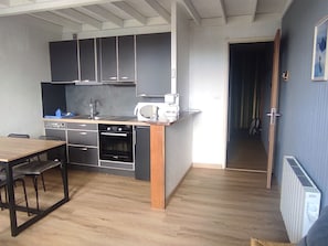 A compact kitchen with a built-in oven, microwave, and a small dining area with a table and chairs.