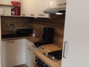 Cozinha compacta com pia, fogão e cafeteira.