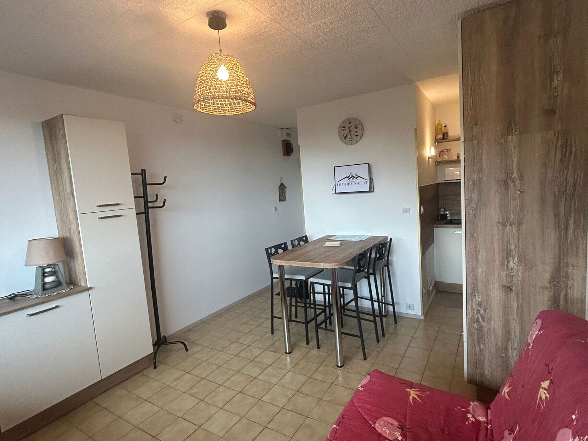 A compact living space with a dining area, kitchenette, and a coat rack.