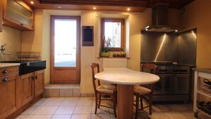 Una cocina con gabinetes de madera, una isla central con sillas, una estufa y una ventana con vistas.
