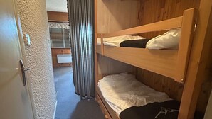 Ein Schlafraum mit Etagenbetten, einer Holztür und einem Vorhang.
