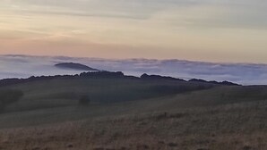 Eine Landschaft mit sanften Hügeln und einem bewölkten Himmel.