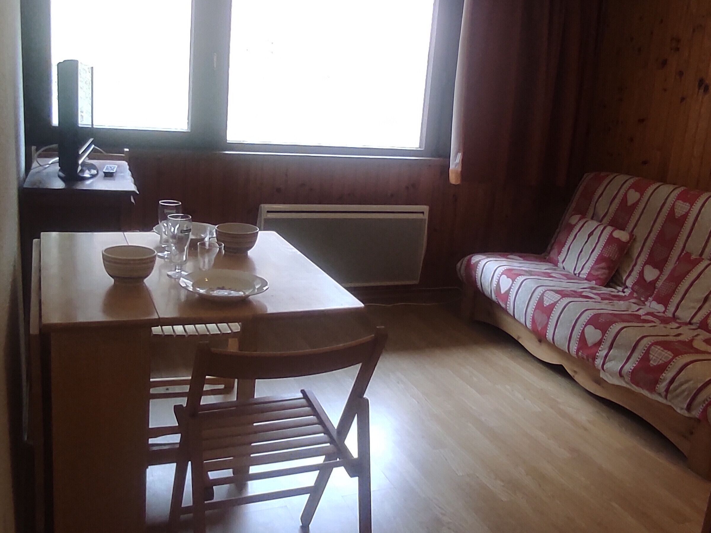 A cozy room with a wooden table, chairs, a sofa, and a window.