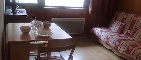 A cozy room with a wooden table, chairs, a sofa, and a window.