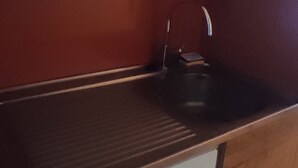 Una cocina con un lavamanos de acero inoxidable, un grifo y una encimera.