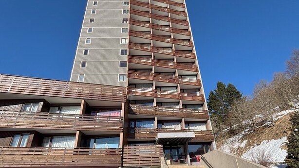 Un edificio de varios pisos con una combinación de elementos arquitectónicos modernos y tradicionales, que incluyen balcones y una entrada destacada.