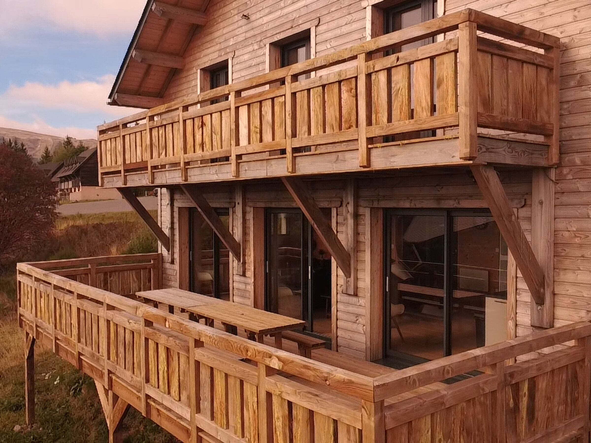 A wooden cabin with a balcony and large windows.