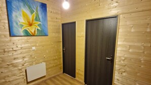 A room with wooden panel walls, two dark doors, a light switch, and a painting of a flower. - Modern chalet for 14 with private parking (Besse-et-Saint-Anastaise-Super Besse)