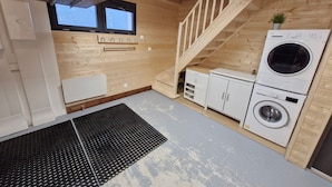 A compact kitchen with wooden walls, a built-in washing machine, and a small window.
