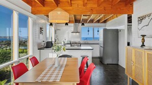 Una cocina moderna con techo de madera, ventanas amplias y vistas al mar.