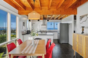 Une cuisine moderne avec un plafond en bois, de grandes fenêtres et une vue sur la mer.