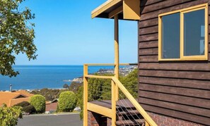 Une maison en bois dotée d’un balcon offrant une vue sur la côte.