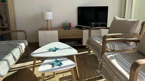 A cozy room with a TV, wooden furniture, and decorative starfish on the wall.