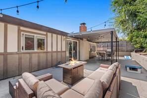 Eine Terrasse im Freien mit Korbmöbeln, einer Feuerstelle und Lichterketten.