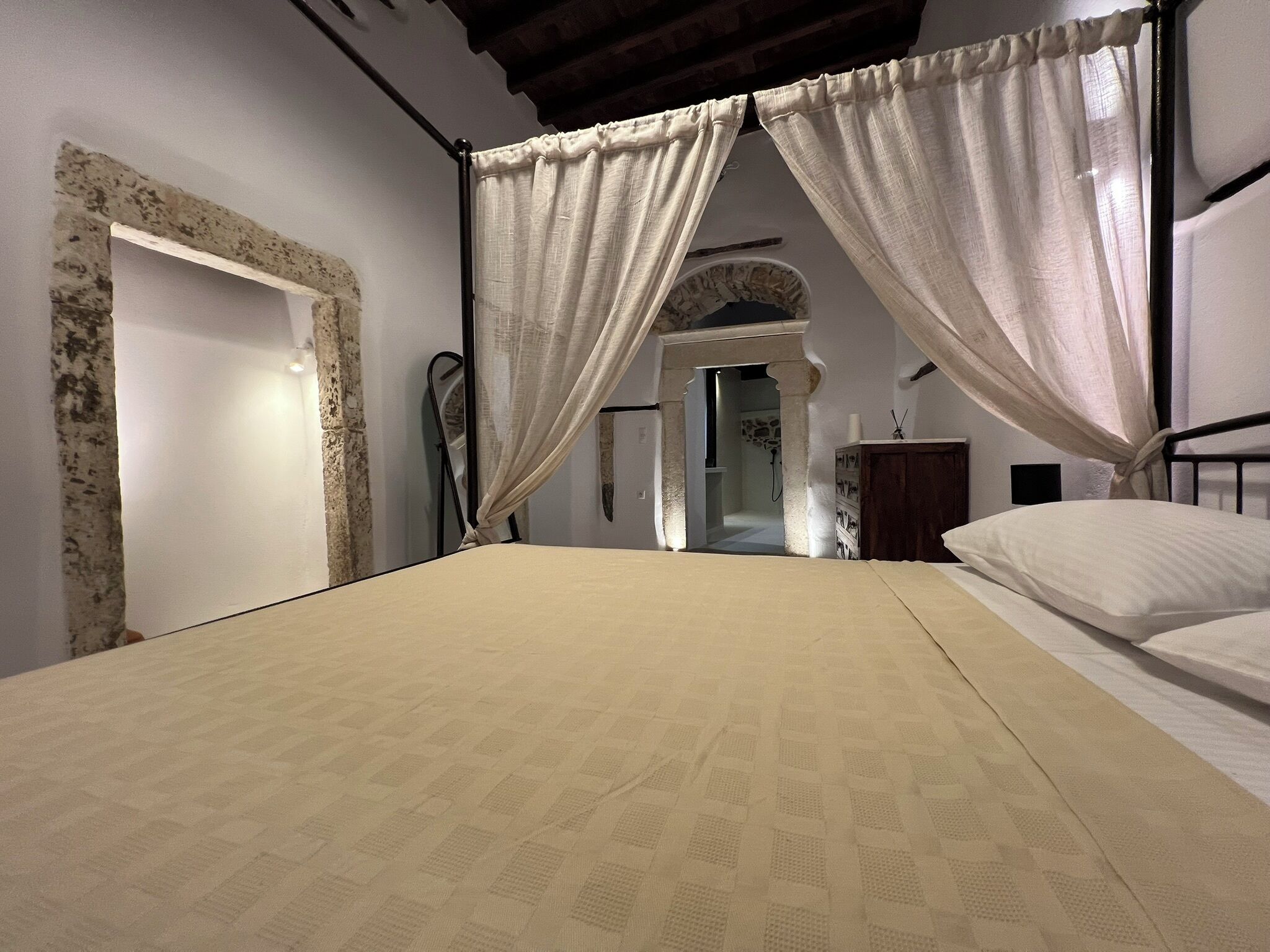 Une chambre à coucher avec un lit, des rideaux, une commode et un miroir.