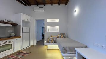 A compact bedroom with a bed, bedside tables, and a small kitchenette.