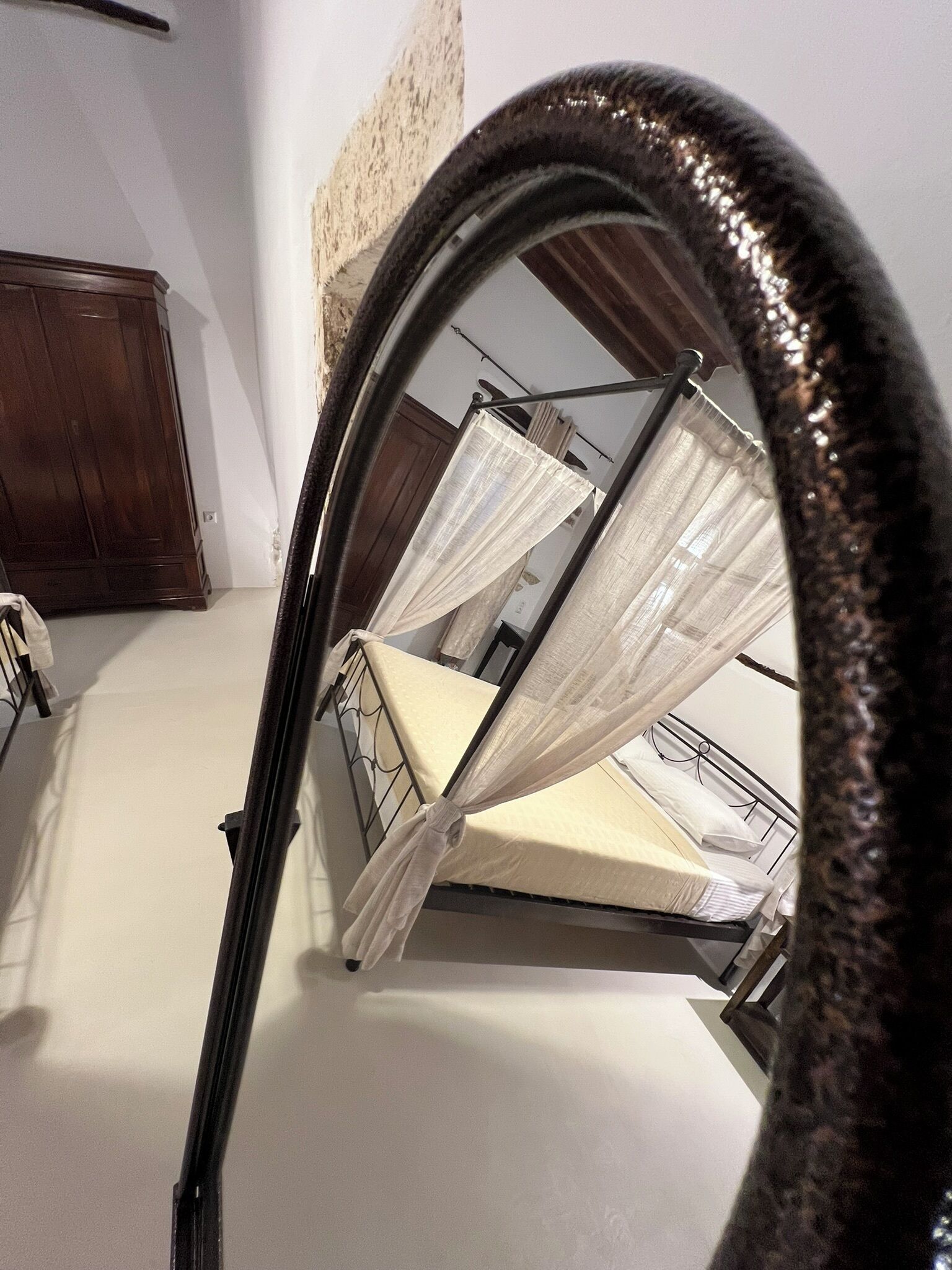 A room with a bed, a wardrobe, and a mirror.