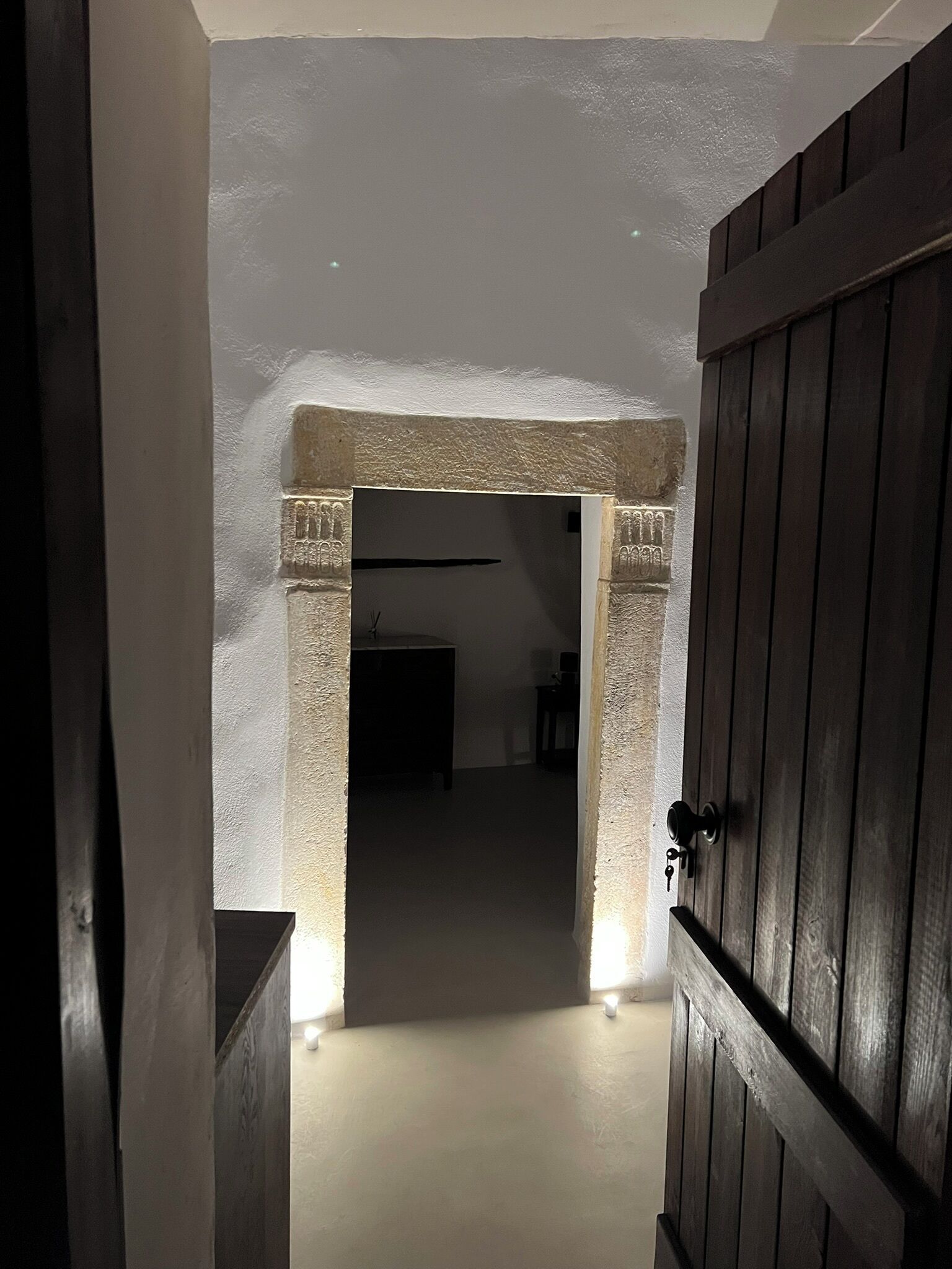 A hallway with a stone archway leading to a room.