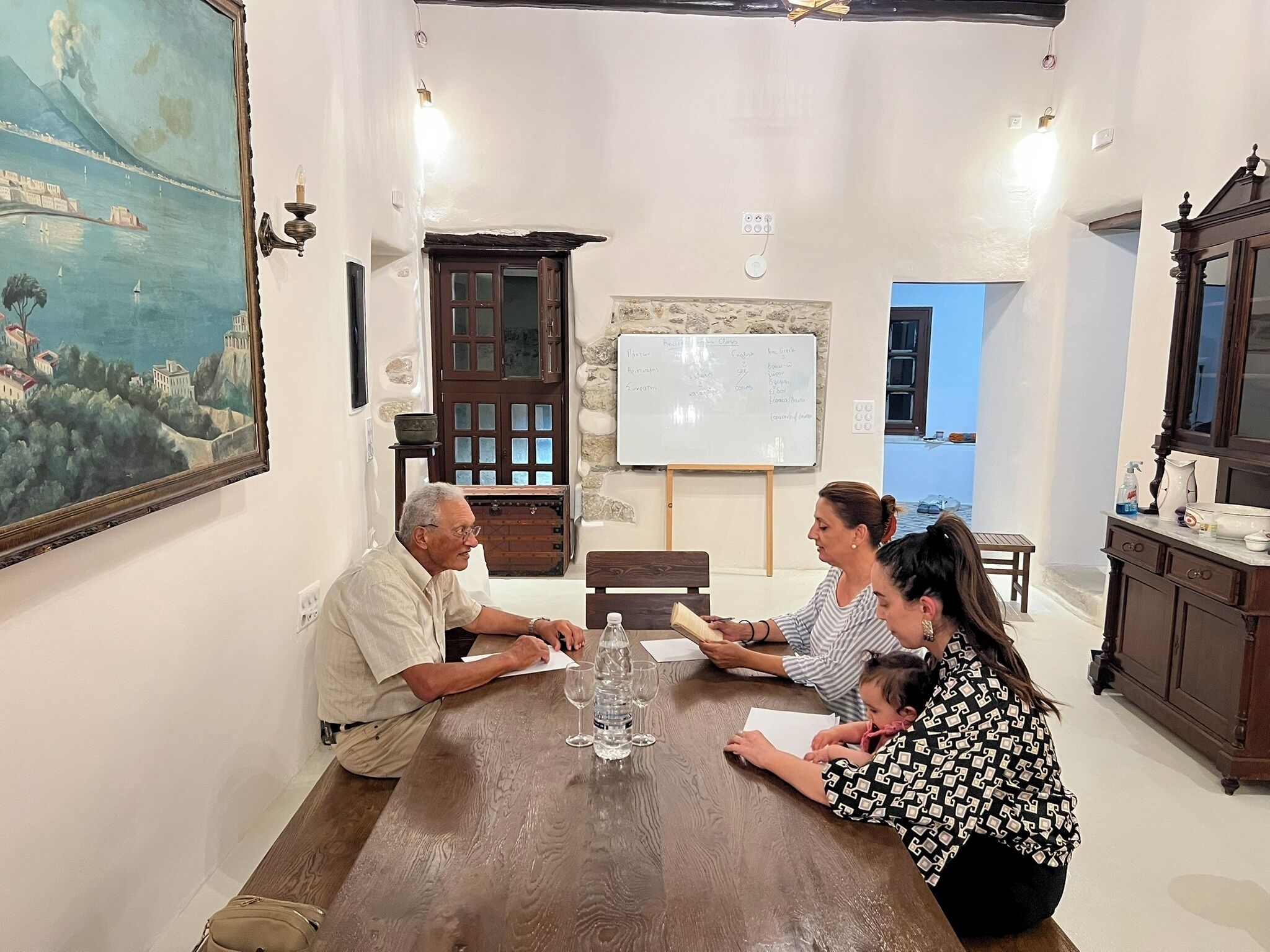 Une salle de réunion avec une table en bois, un tableau blanc et un tableau accroché au mur.