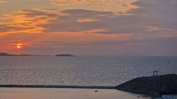 A coastal sunset with calm waters and a small island in the distance.
