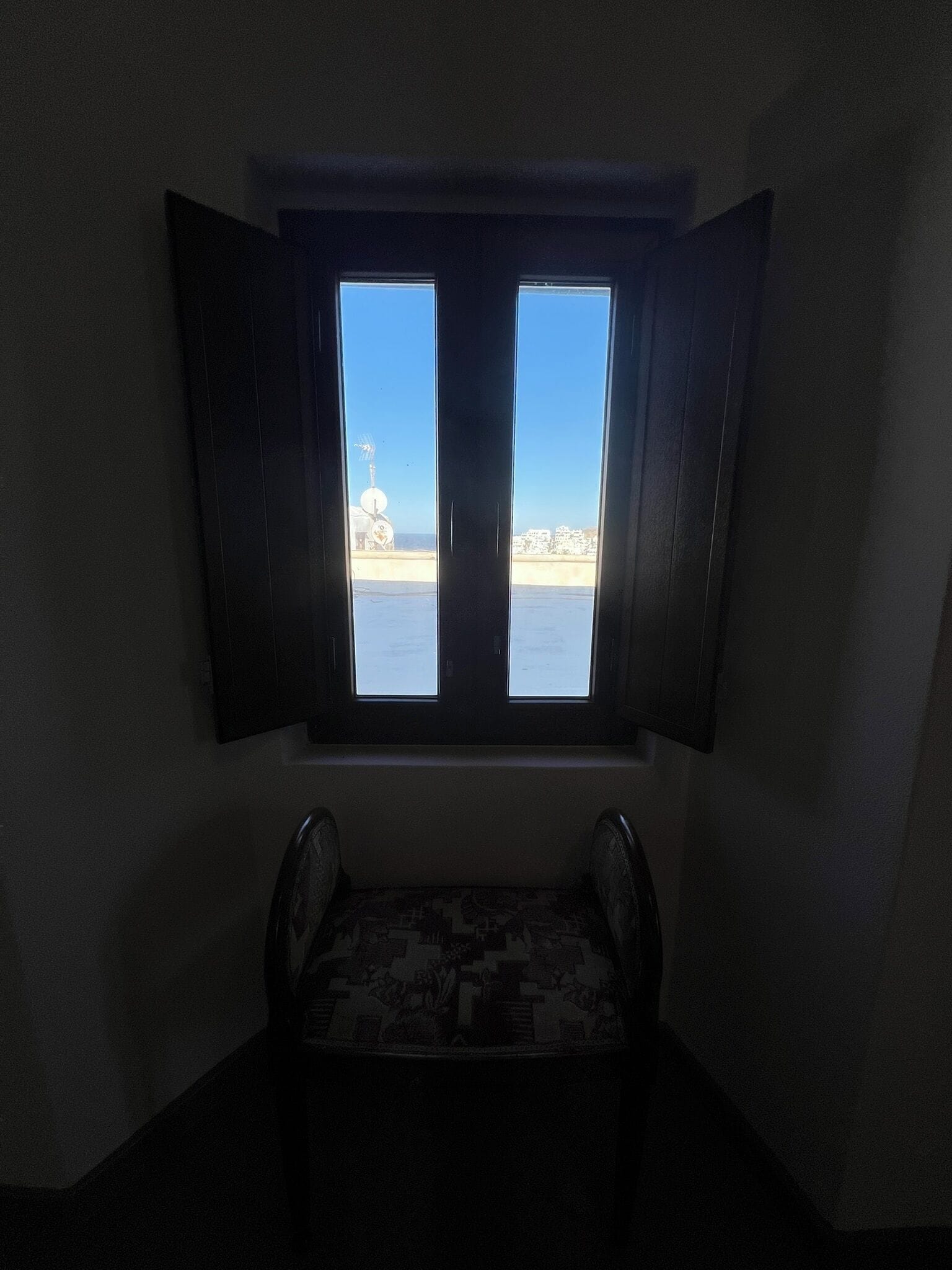 Une chambre avec une petite fenêtre donnant sur une plage.