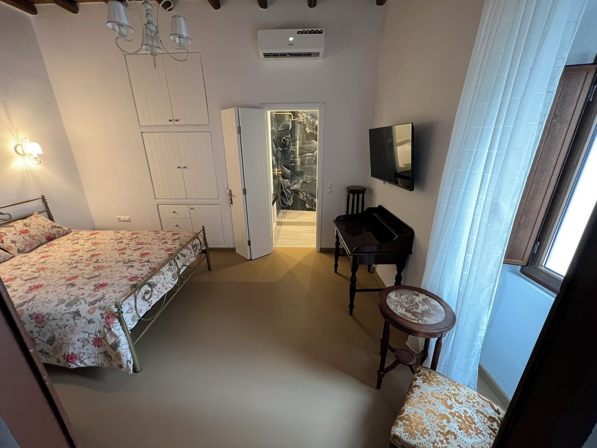 Un dormitorio con cama, escritorio, piano, silla, armario y televisor.