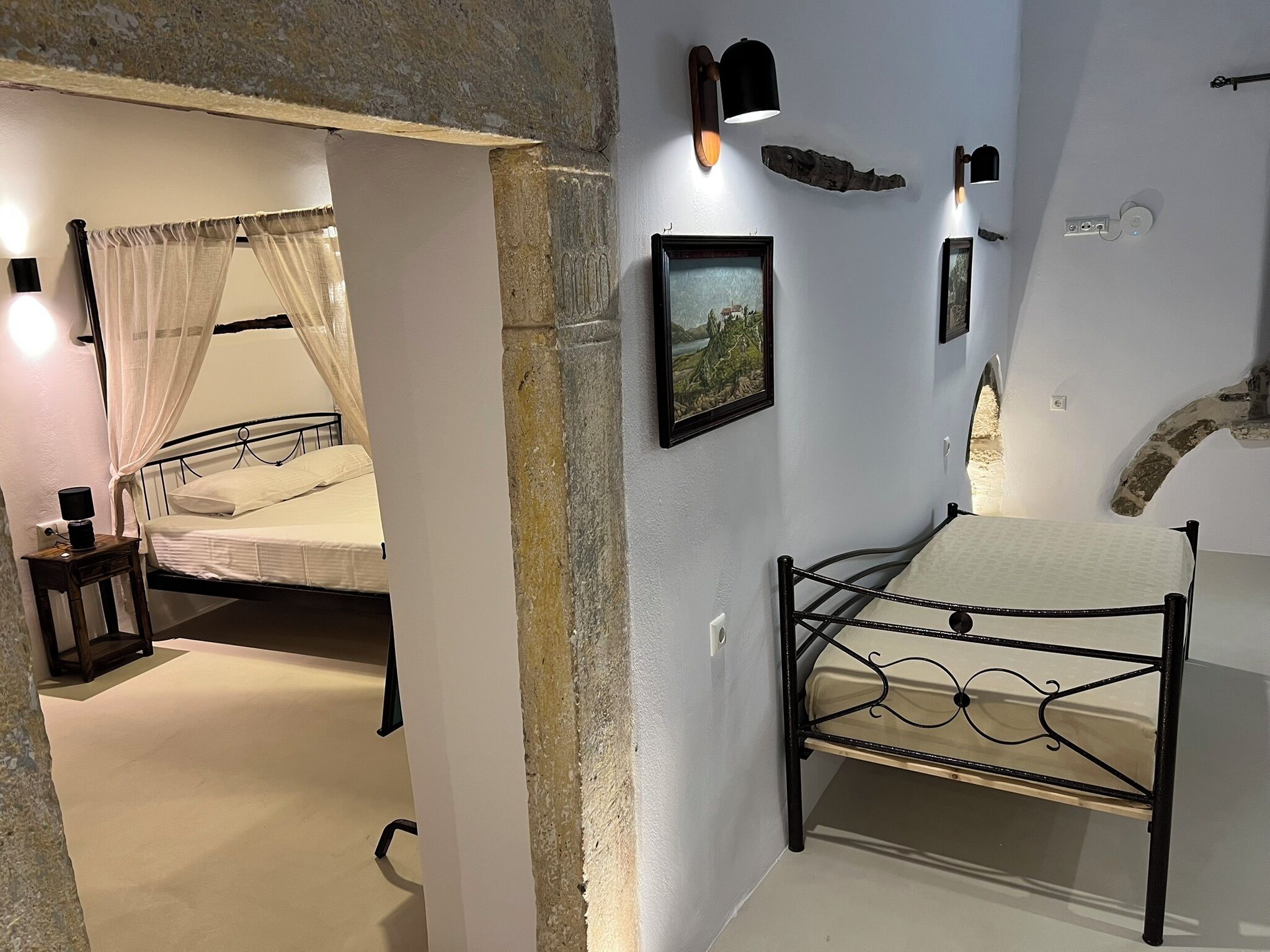 Un dormitorio con una cama, una mesita de noche, una lámpara de pared, un cuadro enmarcado y un adorno en la pared.