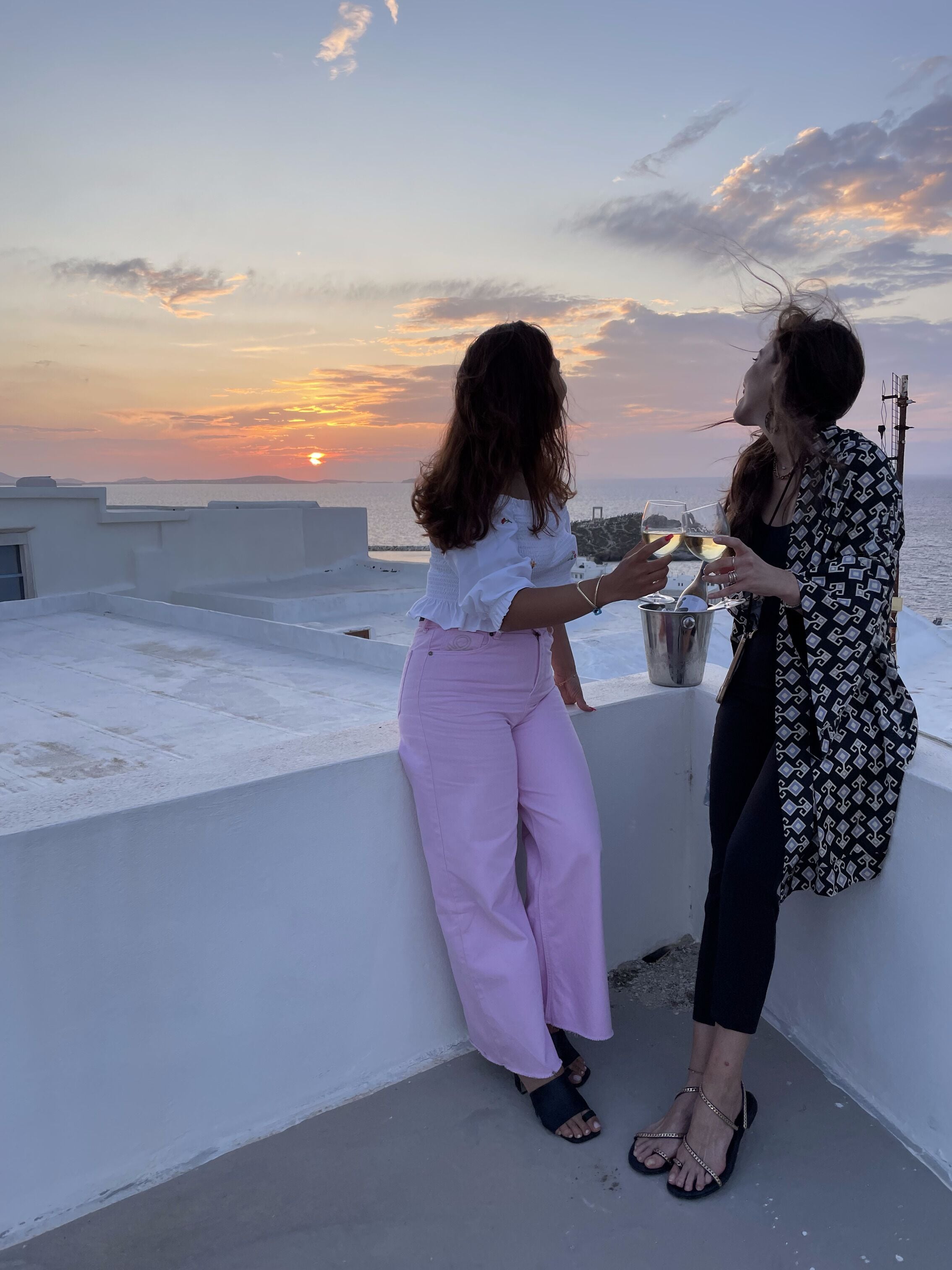 Deux personnes sur une terrasse en toit, avec vue sur le coucher de soleil.
