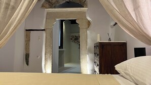Un dormitorio con cama, un armario de madera y una puerta que da a otra habitación.