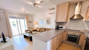A modern kitchen with a central island, built-in oven, microwave, and stainless steel range hood. - 3 Bedroom Apartment on Golf Resort with Pool (Alhama de Murcia)